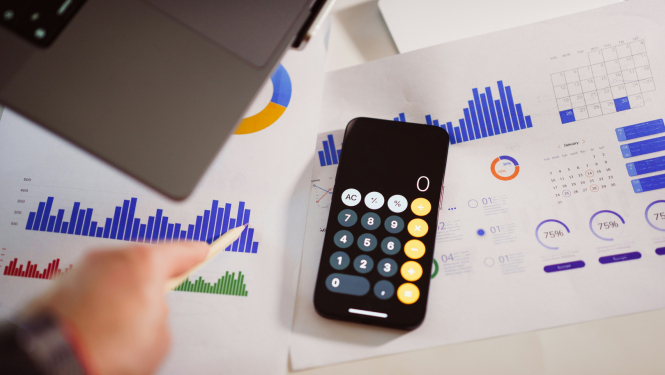 Kalkulators, fonā lapas ar zīmētiem grafikiem