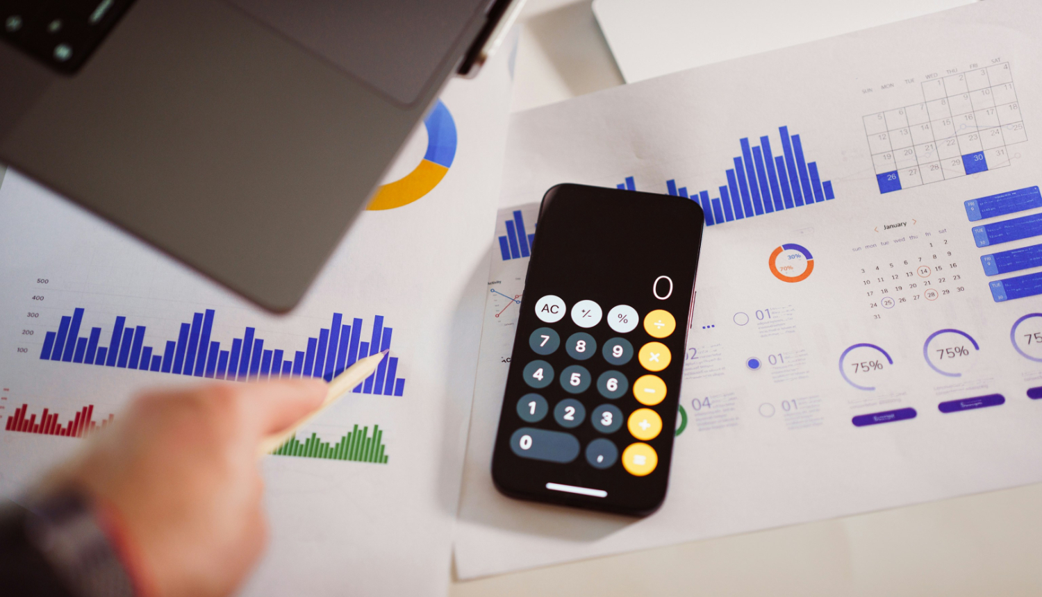 Kalkulators, fonā lapas ar zīmētiem grafikiem