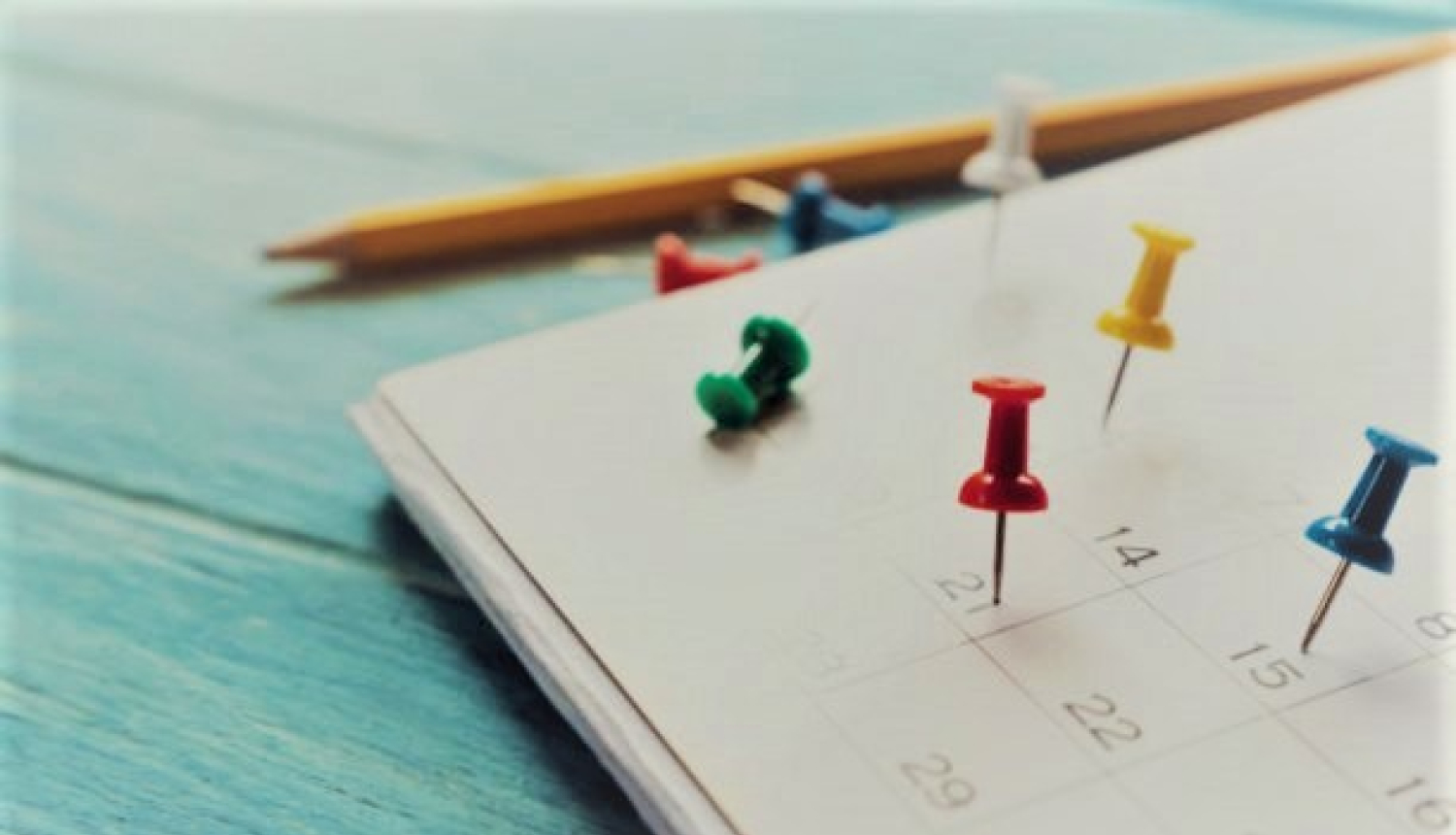 Kalendārs tuvplānā ar kniepadatām un zīmuli