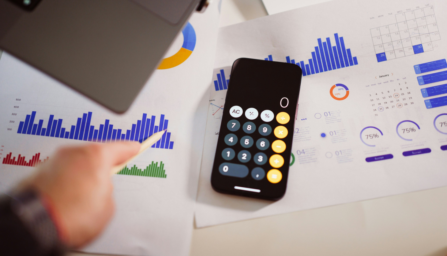 Kalkulators, fonā lapas ar zīmētiem grafikiem